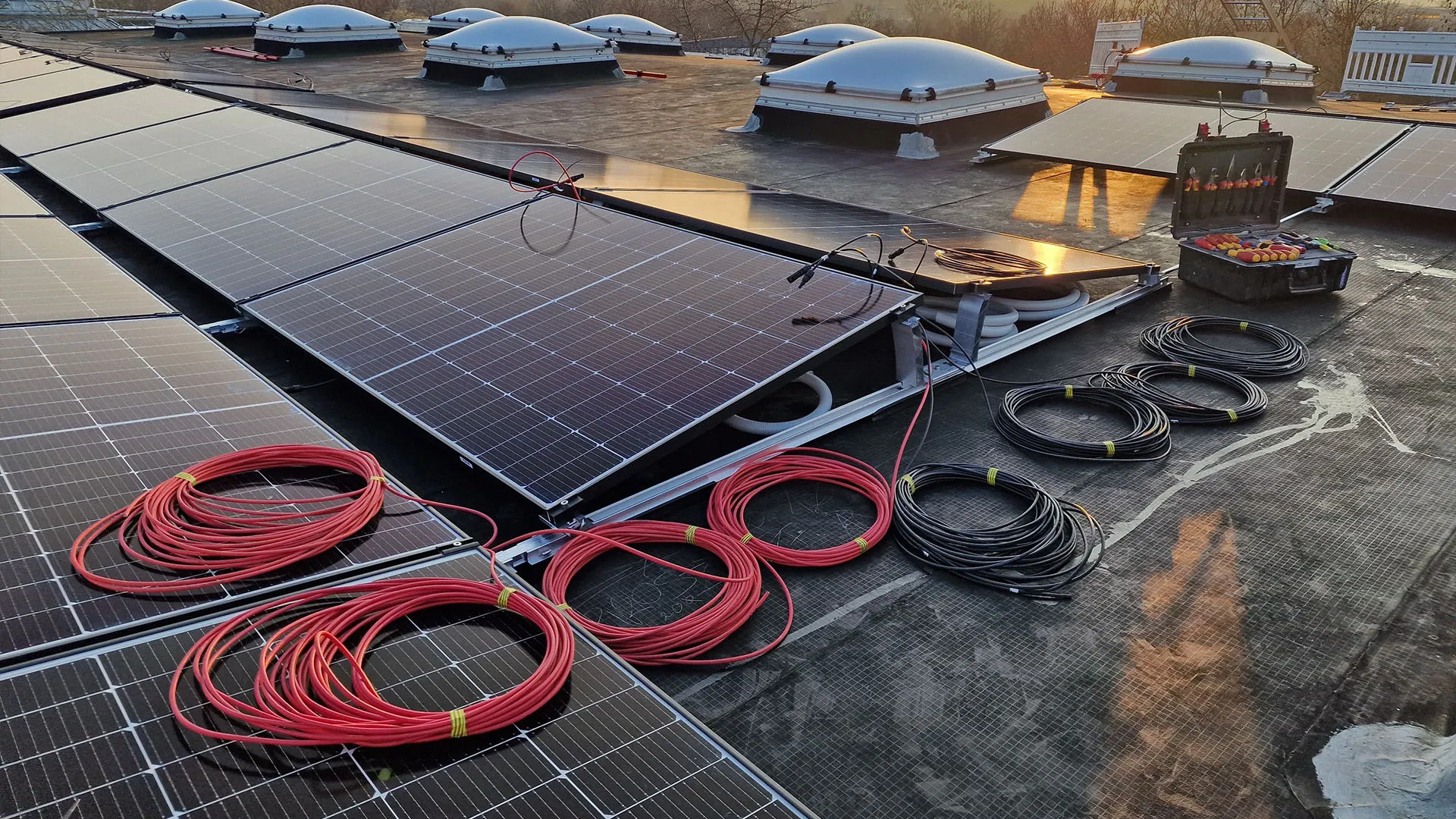Photovoltaikmodule und Leitungen während der Montage auf einem Flachdach